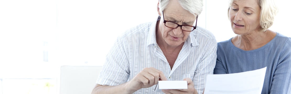 Senior couple seated together looking at documents.